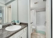 Thumbnail 7 of 25 - A bathroom with a sink, mirror, and shower.
