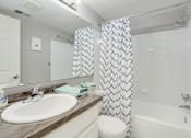Thumbnail 8 of 25 - A bathroom with a white sink and a shower curtain with a black and white pattern.
