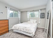 Thumbnail 9 of 25 - A bedroom with a bed, dresser, and mirror.
