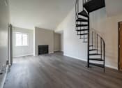 Thumbnail 12 of 23 - Open concept living room with spiral staircase at Alpine Slopes Apartments near Grand Rapids, MI
