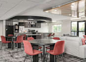 Thumbnail 20 of 25 - A modern kitchen with red chairs and a black table.