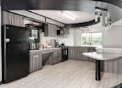 Thumbnail 22 of 25 - A modern kitchen with a black fridge and wooden cabinets.