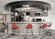 Thumbnail 21 of 25 - A modern bar area with a curved counter and three red stools.