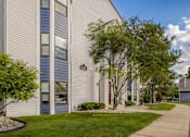 Thumbnail 20 of 20 - a white building with a sidewalk and trees in front of it