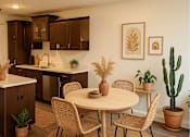 Thumbnail 1 of 30 - A kitchen with a table and chairs and a cactus.