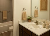 Thumbnail 6 of 30 - A bathroom with a white sink, brown drawers, and a white toilet.
