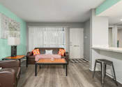 Thumbnail 16 of 34 - A living room with a brown couch and a coffee table.