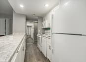 Thumbnail 13 of 34 - A white kitchen with a marble counter top.