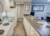 Thumbnail 3 of 34 - A kitchen with white appliances and cabinets.