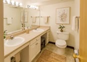 Thumbnail 14 of 20 - A bathroom with a toilet, sink, and mirror.