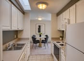 Thumbnail 10 of 20 - A kitchen with white cabinets and a table set for two.