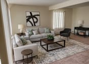 Thumbnail 1 of 20 - A living room with a grey couch, a black chair, a wooden coffee table, and a painting on the wall.