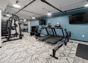 Thumbnail 23 of 26 - a spacious fitness room with cardio equipment and a flat screen tv