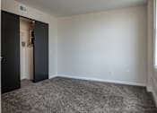 Thumbnail 28 of 50 - an empty living room with carpet and a door to a closet