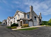 Thumbnail 26 of 26 - a house with a stone chimney and a white garage door