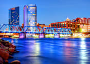 Thumbnail 26 of 27 - A bridge over a body of water with buildings in the background.