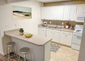 Thumbnail 1 of 15 - a kitchen with white cabinets and a counter with two stools