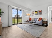 Thumbnail 9 of 21 - a living room with a couch and a coffee table and a sliding glass door  at Park On Canal Apartments, Michigan, 48038
