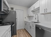Thumbnail 4 of 73 - an empty kitchen with white cabinets and stainless steel appliances