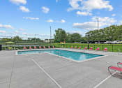 Thumbnail 21 of 50 - a swimming pool with chairs around it and a grassy field in the background