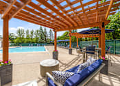 Thumbnail 20 of 33 - A wooden pergola over a poolside seating area.