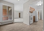 Thumbnail 28 of 35 - a living room with a large window and a kitchen in the background