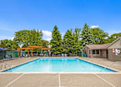 Thumbnail 21 of 33 - A large swimming pool surrounded by trees and a building with a red roof.