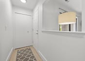 Thumbnail 14 of 33 - A hallway with a rug on the floor and a lamp on the wall.