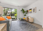 Thumbnail 5 of 33 - A living room with a grey couch, a black table, and a grey rug.