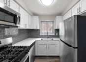 Thumbnail 1 of 32 - a kitchen with white cabinets and stainless steel appliances and a window