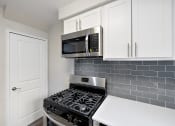 Thumbnail 3 of 32 - a kitchen with a stove and microwave and white cabinets