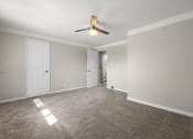 Thumbnail 18 of 32 - a spacious living room with carpet and a ceiling fan