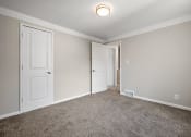 Thumbnail 17 of 32 - an empty bedroom with two doors and a carpeted floor