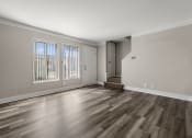 Thumbnail 11 of 32 - an empty living room with wood flooring and a door to a hallway