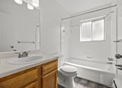 Thumbnail 11 of 26 - A white bathroom with a wooden vanity and a white toilet.