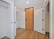 Thumbnail 16 of 38 - A hallway with a wooden door and white walls.