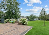 Thumbnail 42 of 50 - a paver patio with a table and chairs in the middle of a grassy area