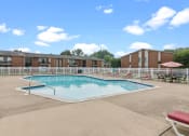 Thumbnail 21 of 35 - a swimming pool with chaise lounge chairs and tables in front of a brick building