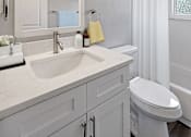 Thumbnail 16 of 28 - A white bathroom with a sink, toilet, and mirror.