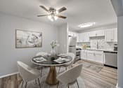 Thumbnail 18 of 28 - A modern dining room with a table set for two and a kitchen in the background.