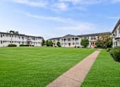 Thumbnail 30 of 33 - a lawn in front of a row of apartment buildings