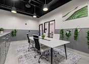 Thumbnail 50 of 58 - A modern office space with a white desk, black chairs, and greenery on the walls.