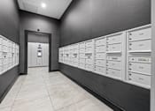 Thumbnail 51 of 58 - A hallway with a series of mailboxes on the wall and a door at the end.