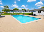 Thumbnail 16 of 18 - A large swimming pool in front of a building with a white exterior.