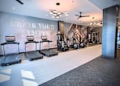 Thumbnail 23 of 31 - a fitness room with treadmills and other exercise equipment
