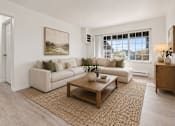 Thumbnail 11 of 35 - A living room with a white couch, a brown coffee table, and a painting on the wall.