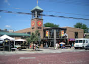 Thumbnail 37 of 39 - A brick building with a clock tower in the middle of a street.