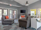 Thumbnail 16 of 24 - A living room with grey chairs, a white cabinet, and a flat screen TV.