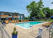 Thumbnail 26 of 28 - A pool area with a fence and a building in the background.