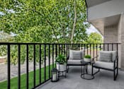 Thumbnail 26 of 38 - A balcony with two chairs and a table with a plant on it.